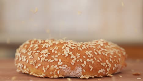 Sesame-Seeds-Falling-on-Freshly-Baked-Bagel,-Close-Up-with-Copy-Space