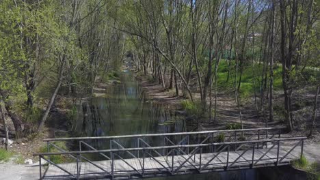 Kleine-Holzbrücke-über-Einen-Flachen-Bach-Zwischen-Wäldern-Tagsüber
