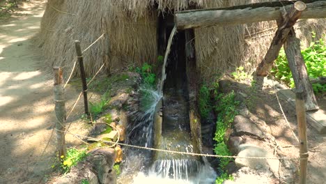 Water-flowing-through-open-wooden-pipes-filling-wooden-water-mill-for-milling-wheat-and-rice-in-Korean-folk-village-Yongin-City,-Korea