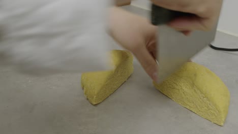 Cutting-the-pasta-dough-into-four-pieces-on-kitchen-cooking-table