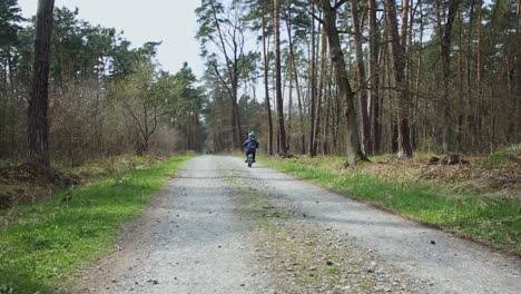 Small-boy-ride-on-bicycle-in-spring-forest,-healthy-outdoor-recreation
