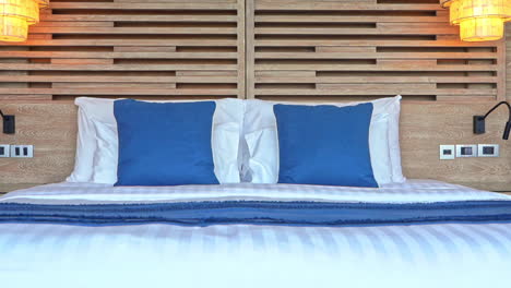 Schwenken-Sie-über-Ein-Großes-Bequemes-Bett,-Das-Mit-Einer-Blauen-Decke-Und-Dekorativen-Kissen-Dekoriert-Ist