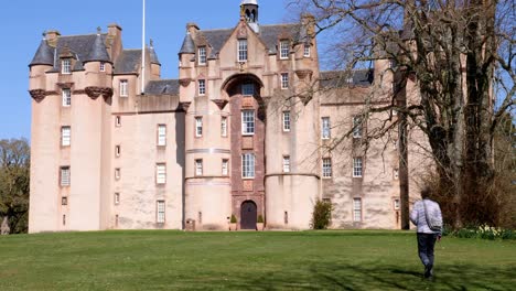 Lady-walker-walks-towards-the-front-of-Fyvie-castle-on-a-lovely-spring-morning