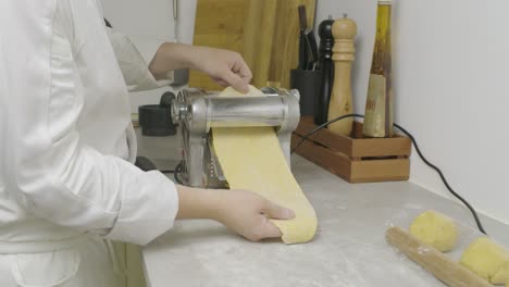 Passing-pasta-dough-through-cooking-press-machine.-Closeup