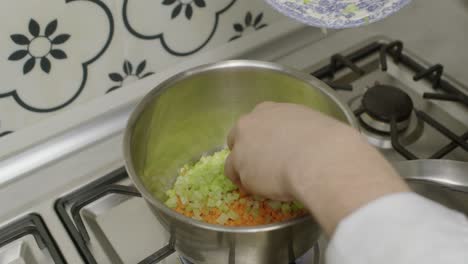Adding-diced-celery-into-cooking-pot-with-diced-carrots