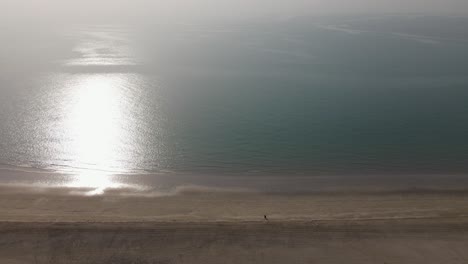 Drone-view-of-two-Arab-women-walking-on-the-beach,-United-Arab-Emirates