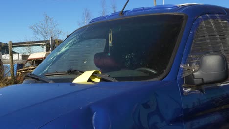 Blue-car-with-a-Broken-window-in-a-junkyard