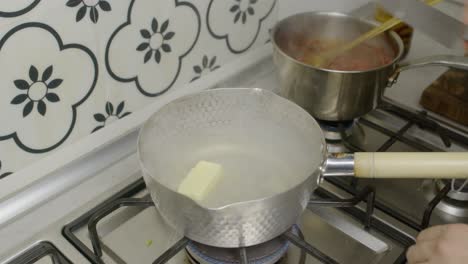 Adding-piece-of-butter-into-hot-metal-cooking-pot