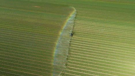 Spraying-water-vapor-from-long-tractor-arms-creating-rainbow-in-tulip-field