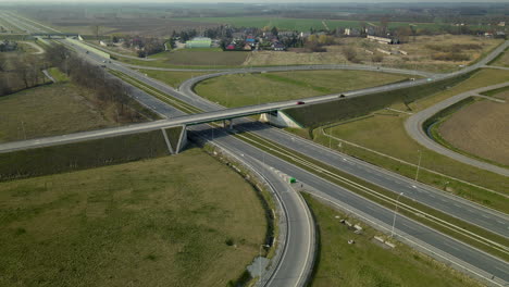 Aerial-tilt-down-view-over-highway-exit-ramp-travel-with-traffic-through-Cedry-Poland