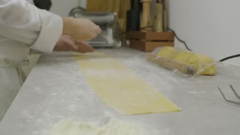 Chef-adds-flour-onto-the-pasta-dough-on-the-kitchen-table