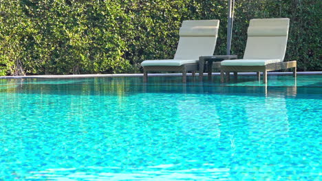 Zwei-Liegestühle-Und-Ein-Kleiner-Tisch-Im-Seichten,-Türkisfarbenen-Poolwasser-Des-Tropical-Thailand-Hotel-Resort
