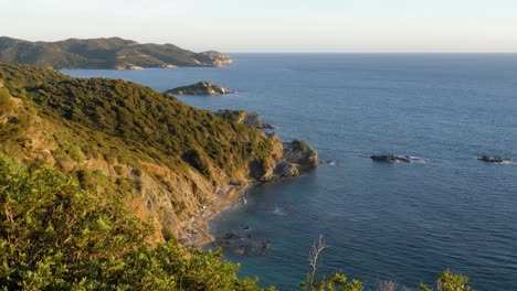 Schöne-Felsige-Küste-Mit-Vegetation-In-Goldener-Nachmittagssonne-Und-Blauem-Wasser-In-Chia,-Südsardinien,-Italien