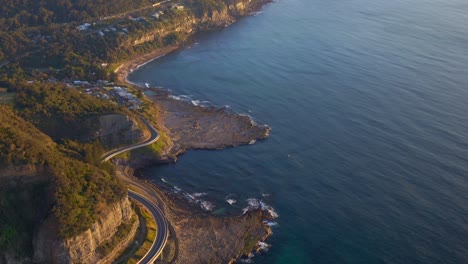 Aerial-View-Of-Winding-Road-In-Sea-Cliff-Bridge-At-Sunrise-In-Clifton,-Australia