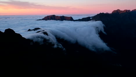 Time-lapse-of-clouds-rolling-off-the-side-of-a-mountain-in-Maderia,-Portugal-at-sunset