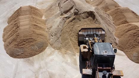 Aerial-view-of-a-tractor-moving-a-load-of-fresh-sand-at-a-concrete-plant