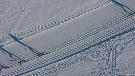Aerial-birds-eye-showing-line-of-skier-athletes-skiing-on-snowy-winter-path-during-competition-in-winter