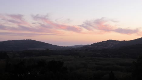 Beautiful-soft-pink-light-in-cloudy-sky-at-dusk-with-Mediterranean-landscape-and-hills-in-Chia,-Southern-Sardinia,-Italy