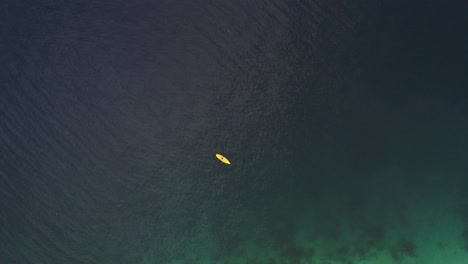 Hombre-Acostado-En-Un-Bote-De-Kayak-Flotando-En-El-Océano-Sereno-De-La-Isla-De-San-Pablo-En-El-Sur-De-Leyte,-Filipinas