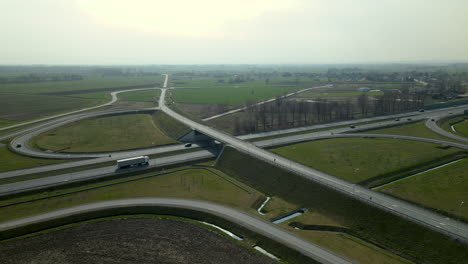Aerial-view,-the-drone-flies-along-infinity-highway-road-interchange-with-light-urban-traffic-speeding-on-the-road