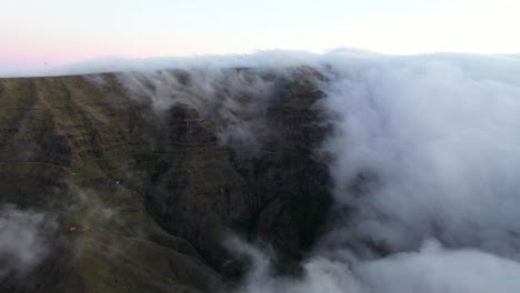 Drohnen-Luftaufnahmen-Von-Wolken,-Die-Von-Einem-Berg-Auf-Der-Insel-Madeira,-Portugal,-Abrollen