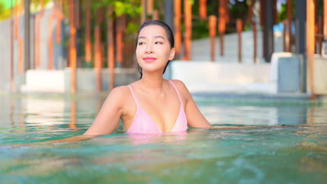 Schönes-Lächelndes-Asiatisches-Model,-Das-Urlaub-Im-Swimmingpool-Des-Resorts-Genießt