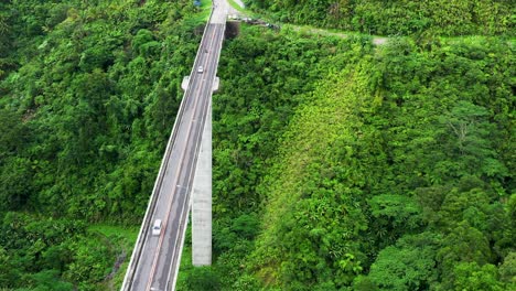 Puente-Agas-agas,-Sogod,-Leyte-Del-Sur,-Filipinas---Vista-De-Los-Vehículos-Que-Cruzan-El-Largo-Puente-De-Vigas-De-Hormigón-Situado-En-Montañas-Cubiertas-De-árboles-Verdes-Y-Pastos---Toma-Aérea-De-Drones