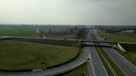 Aerial-shot-of-modern-driving-highway-in-Poland-during-sunny-and-cloudy-day-near-countryside-fields