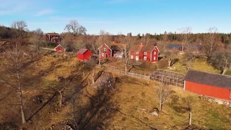 AERIAL---Red-wooden-houses,-Asens-By-Culture-Reserve,-Sweden,-wide-shot-forward