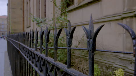 Black-wrought-iron-fence-against-a-sandstone-cathedral-wall