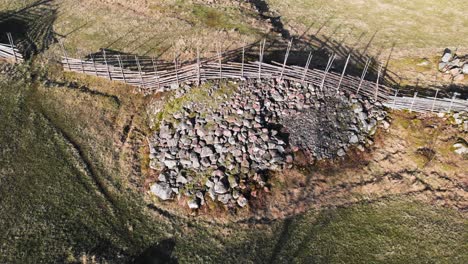 Aerial-Shot-Of-Ancient-Nordic-Farm-Fence-In-A-Agricultural-Field-With-Stone-Rock-Pile-Below