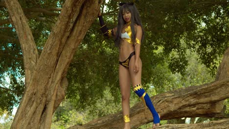 Left-pan-of-a-cosplay-anime-girl-standing-on-a-large-tree-branch-as-an-Ishtar-Goddess