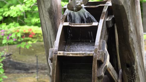 Water-flowing-into-the-wooden-sections-of-korean-traditional-water-wheel-in-Namsan-Park,-South-Korea