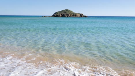 Clear-shallow-turquoise-water-with-little-rocky-island-in-the-horizon-in-South-Sardinia,-Italy