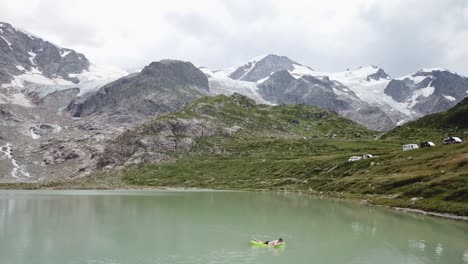 Vuelo-De-Drones-Sobre-El-Lago-Y-El-Glaciar-Stein-Con-Un-Hombre-En-Un-Colchón-De-Aire-En-Los-Alpes-De-Urner-En-Suiza