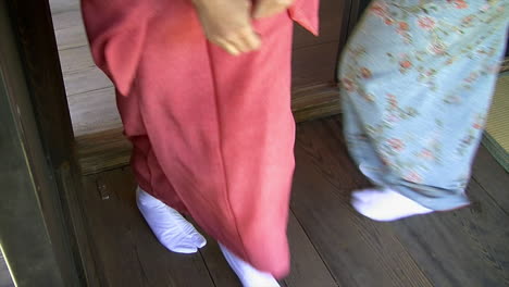 Japanese-women-wearing-kimonos-and-tabi-socks-walk-through-doorway-on-hinoki-wood-floor