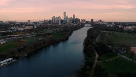 4k-Aerial-drone-slow-pan-up-of-downtown-Austin,-Texas-Skyline-and-Ladybird-lake-at-sunset