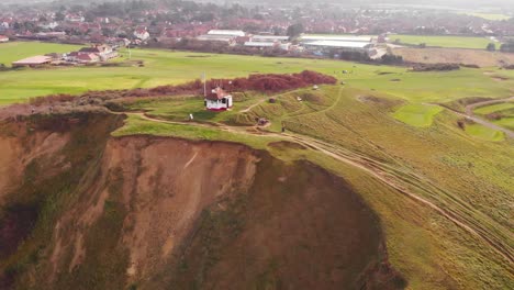Aerial---Golf-course-and-cliffs-in-Sheringham,-England,-wide-spinning-shot