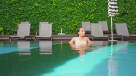 Attractive-Asian-Woman-Resting-in-Outdoor-Hotel-Swimming-Pool-SLOMO