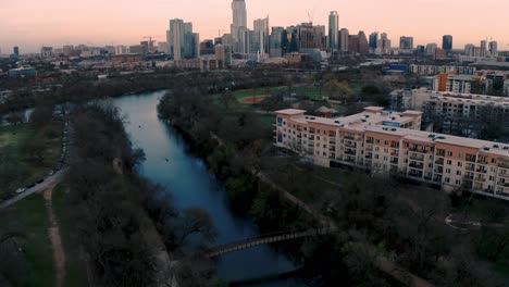 Downtown-Austin-Texas-Skyline-and-Ladybird-Lake-at-sunset,-aerial-drone-pull-away-in-4k