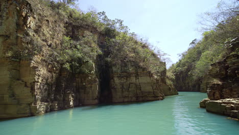 Navigating-trough-canyons-of-sedimentary-rocks,-vegetation-and-green-water