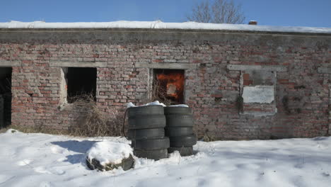 Bomb-blast-explodes-in-old-brick-building-with-tires-stacked-outside-in-snow