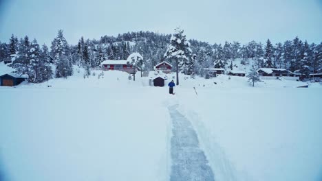Man-Sled-Shoveling-Mass-Of-Snow-In-Winter-Foreground-Making-A-Pathway-At-Rural-Area-Near-Trondheim,-Norway