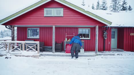 Mann-In-Winterkleidung-Mit-Kapuze-Bekommt-Eine-Schaufel-Und-Eine-Schlittenschaufel-In-Der-Hütte-In-Trondheim,-Norwegen