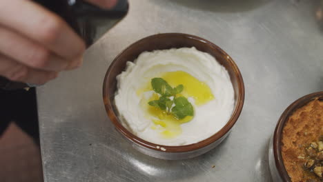 Chef-Sirviendo-Un-Plato-De-Yogur-De-Entrada-Mediterráneo,-Agregando-Aceite-De-Oliva-En-La-Parte-Superior