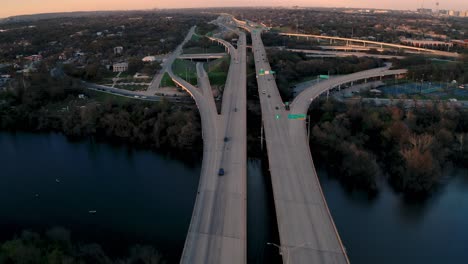 Austin,-Texas-commuters-driving-home-from-work-on-Mopac-Expressway-at-sunset,-drone-aerial-over-Ladybird-Lake-4k