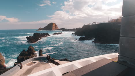 POV-shot-walking-towards-waves-crashing-the-shore-of-sunny-Porto-Moniz,-Madeira