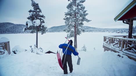 Man-At-Work-Carrying-Traditional-And-Modern-Snow-Sled-Shovel