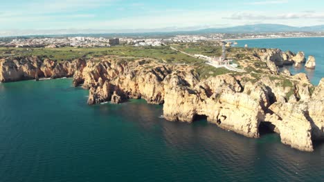 Leuchtturm-Ponta-Da-Piedade,-Umgeben-Von-öden-Landzungen-An-Der-Algarve---Breite-Luftaufnahme-Von-Oben,-Langsame-Umlaufbahnaufnahme