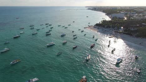 Aerial-reveal-of-Boats-resting-docked-in-the-ocean-at-sunset-blue-water